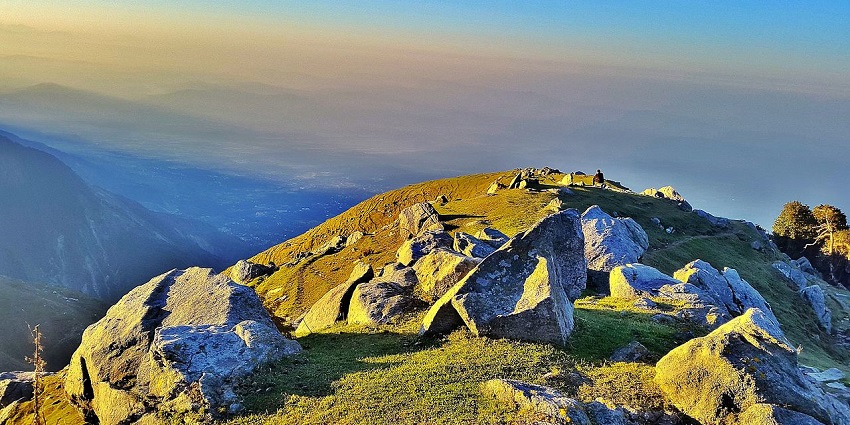 A mesmerising view of sunlight falling on big boulders on a rocky mountain cliff.