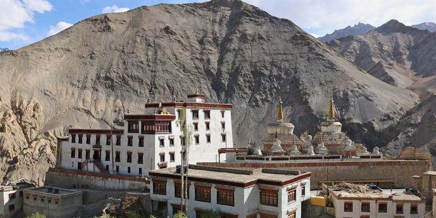 A picture of a Tibetan temple with a white exterior and views of mountain in the background