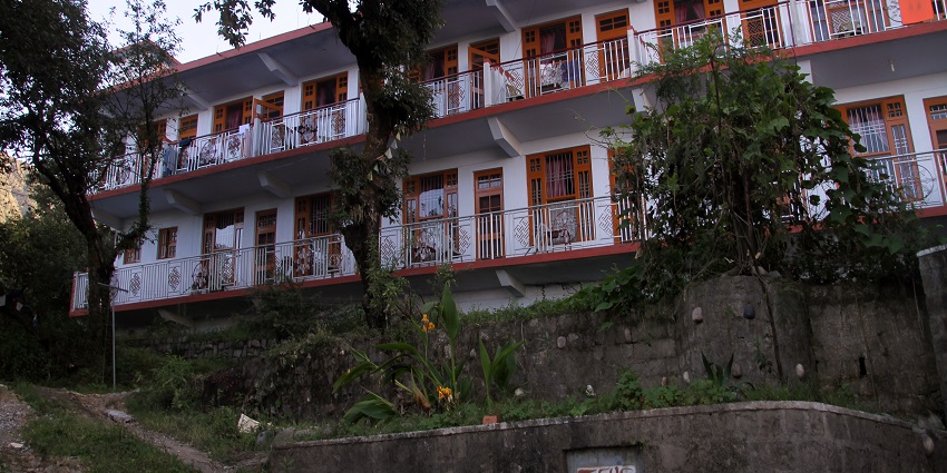 An old monastery in Mcleodganj with white and red walls and greenery around