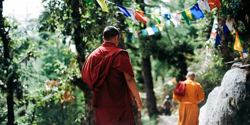 Monks walking between trees, dressed in traditional robes - Spirituality Within Kullu.