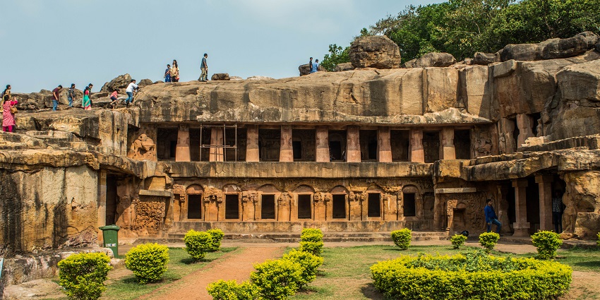 Udayagiri and Khandagiri caves with ancient rock-cut architecture and a lush, green landscape.