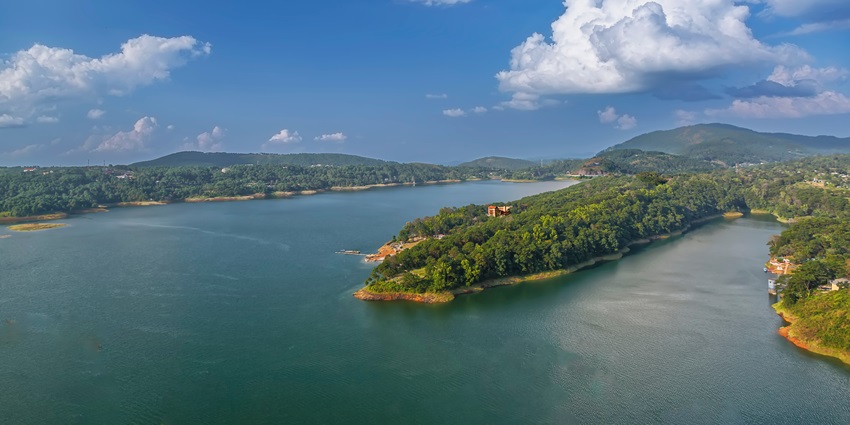 A scenic view of the Umiam Lake featuring lush greenery and shimmering blue waters.