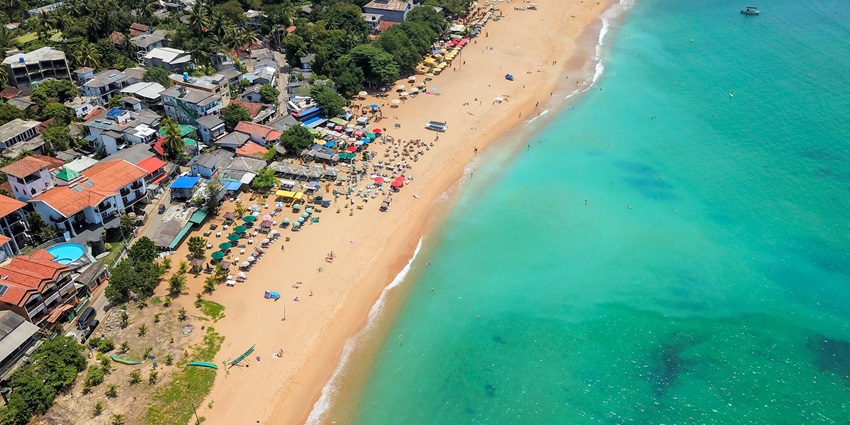 An aerial view of turquoise-blue waters meeting the pristine sands at Unawatuna.