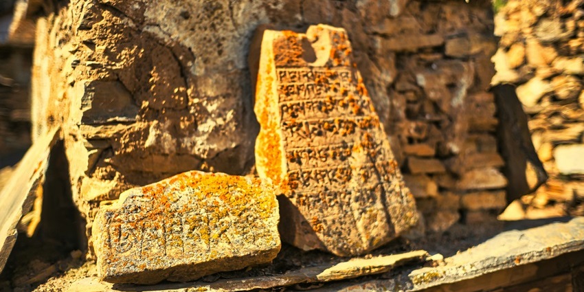 Close-up of neatly stacked stone scriptures arranged in a rustic outdoor setting.
