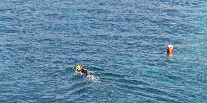 A picture of a person taken with a drone riding an underwater scooter in the sea
