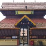 A frontal view of Valayanad Temple with red rood and yellow walls during the daytime.