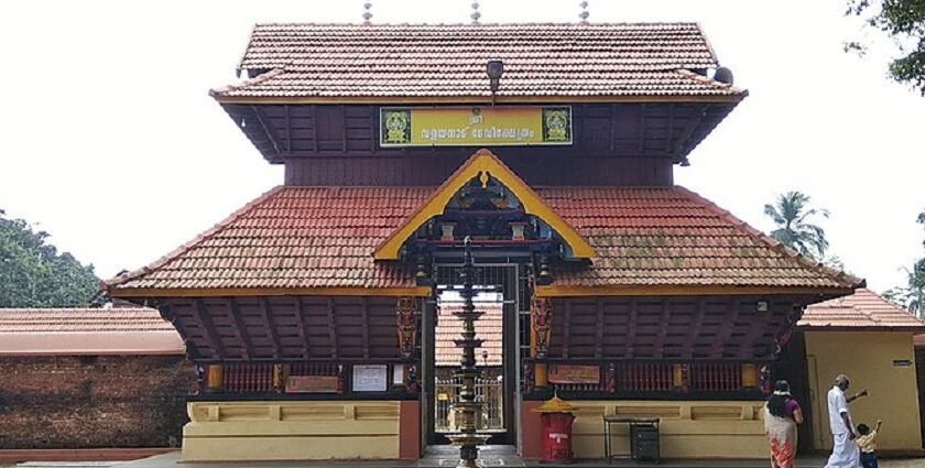 A frontal view of Valayanad Temple with red rood and yellow walls during the daytime.