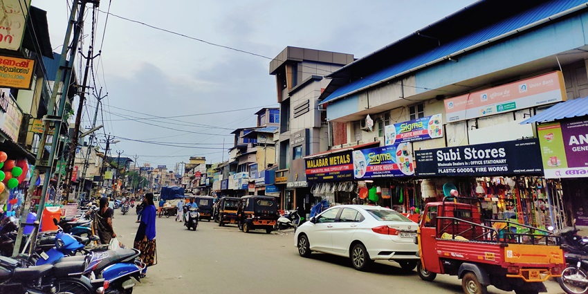 Bustling street bazaar in Palakkad lined with shops, goods and people amid bright daylight