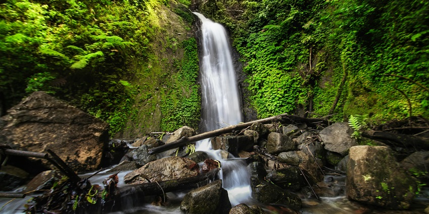 View of Vankhosüng Fall with water plunging over rugged rocks into a tranquil pool.