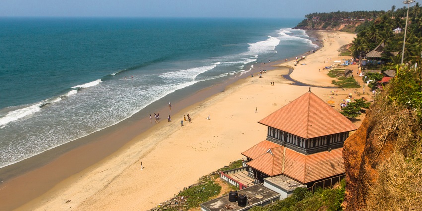 Vibrant Varkala Beach at sunrise, capturing waves, palm trees, and golden light.