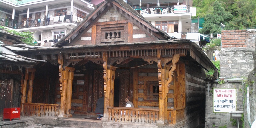 A picture of a traditional Hindu temple in Manali with a priest sitting outside