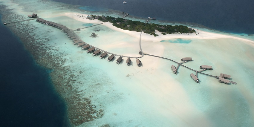 An aerial view of a small island encircled by a coral reef in the Maldives