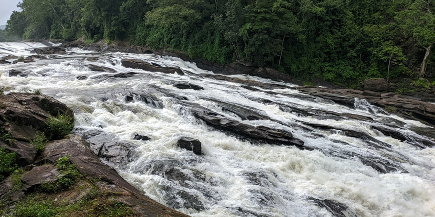 Beautiful picture of Vazhachal Waterfalls following amidst the green hills of Kerala
