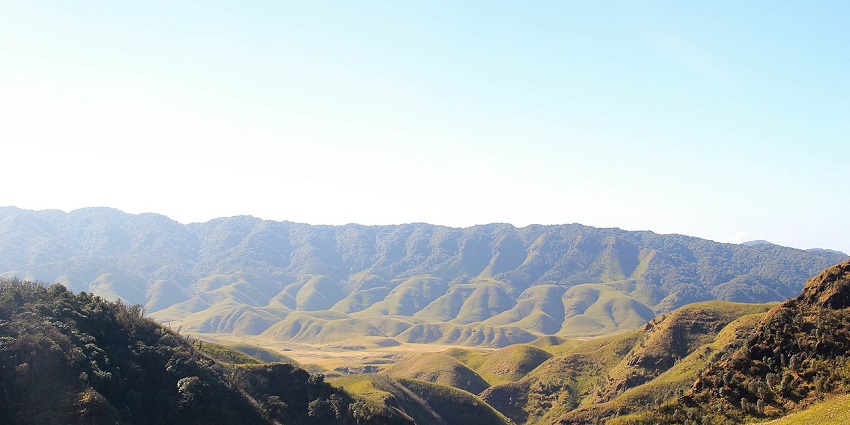 Vibrant sun hues reflecting on the verdant peaks of the hills, offering a mesmerizing view