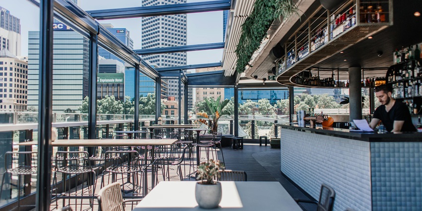 A picture of an elegant rooftop bar with a comfortable seating area and a bar counter