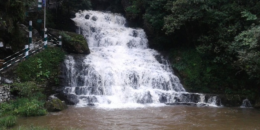 View of Elephant Falls cascading through three tiers, surrounded by lush greenery.
