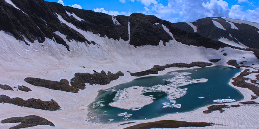 Lake with its pristine waters reflecting the surrounding snow-capped peaks and rugged terrain.