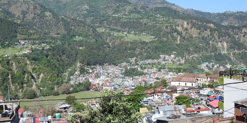 A scenic view of Chamba town, showcasing its lush green hills and traditional architecture.