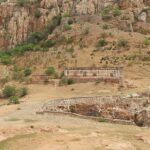 Image of ancient Gooty Fort above mountains, surrounded by rocks and lush greenery.