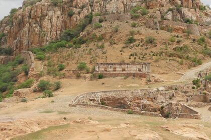 Image of ancient Gooty Fort above mountains, surrounded by rocks and lush greenery.