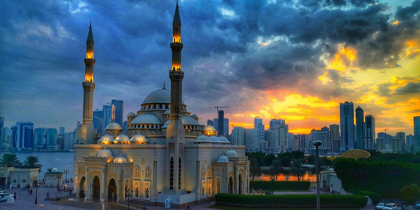 A scenic and captivating view of a mosque during dawn with cars parked on the road.