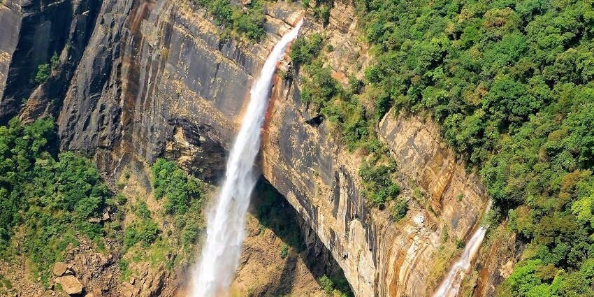 View of Nohkalikai Falls, the tallest plunge waterfall in India, surrounded by green cliffs and misty air.