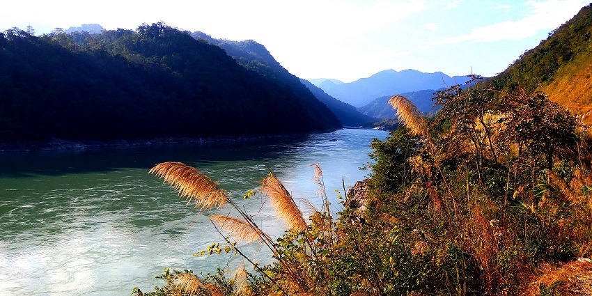 Majestic Siang River flowing through lush greenery and mountains in the background.