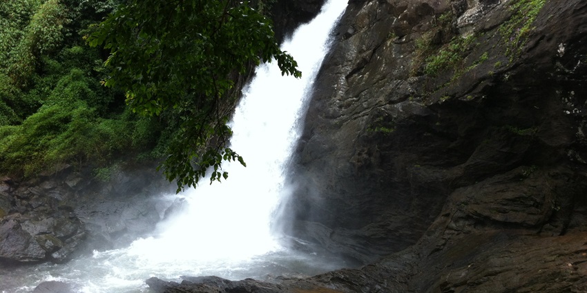 Soochipara Falls, with water cascading down the rocky cliffs surrounded by greenery.