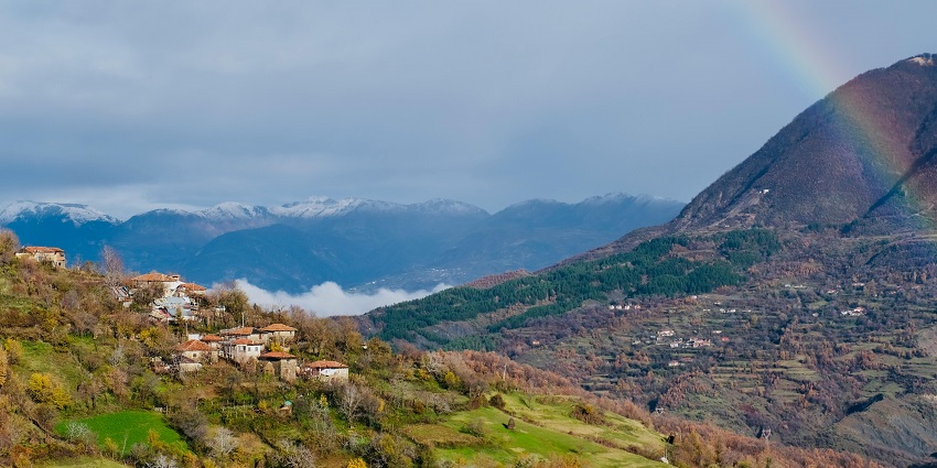 Green and brown mountains stretching under a clear blue sky, breathtaking landscape.