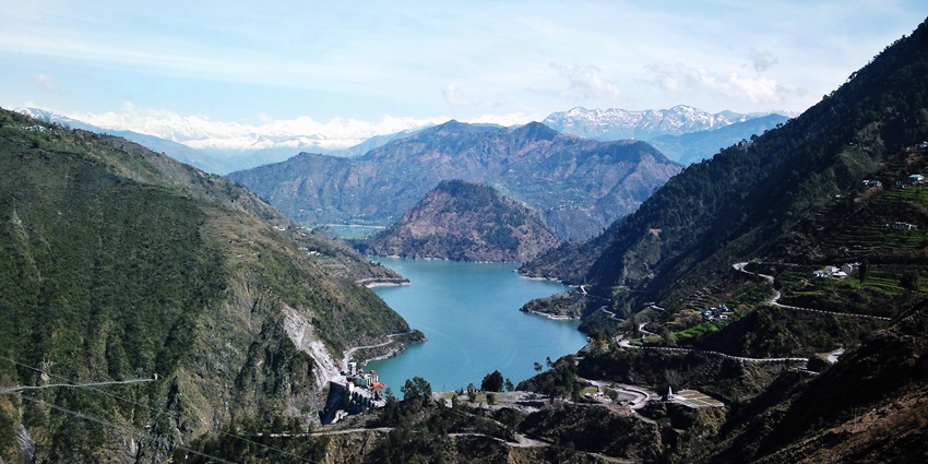 Scenic view of Pir Panjal mountain range and Chamera Lake in Himachal Pradesh, India, showcasing serene blue waters.