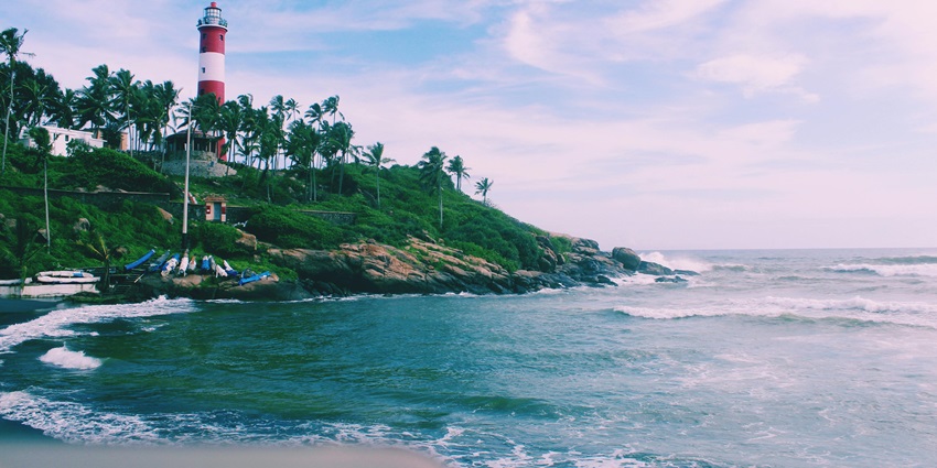 A picture of a lighthouse taken from a distance with views of the ocean and greenery