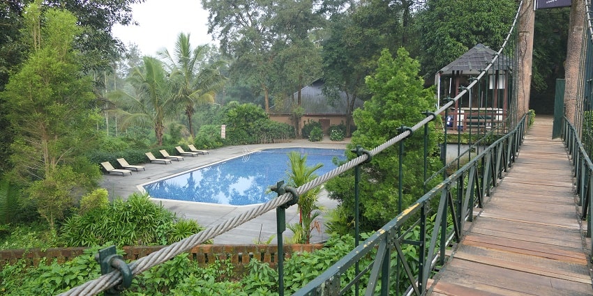 A picture taken from a small bridge at a water park with a swimming pool on the side
