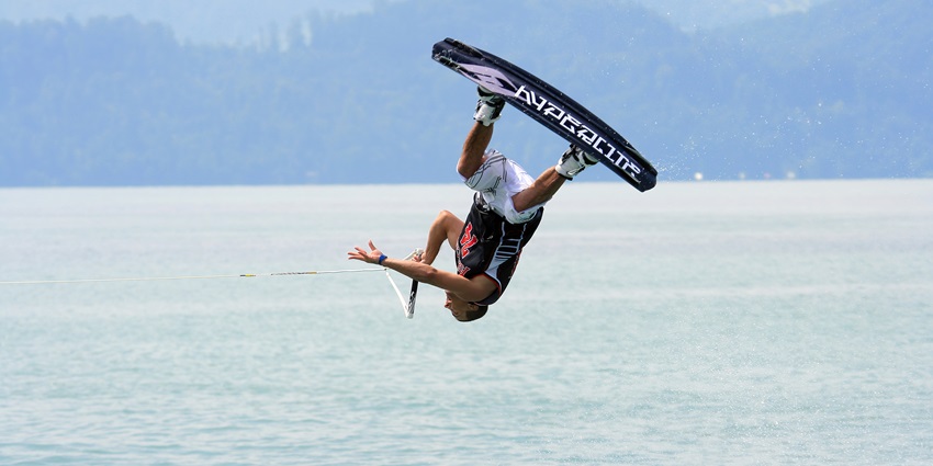 A trained professional performing a stunt while wakeboarding in a water body