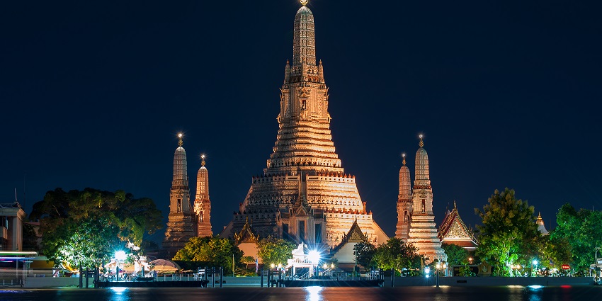 Wat Arun Ratchawararam temple in Bangkok, beautifully lit up against the twilight sky.