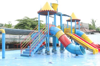 View of a blue, yellow and red water slide and a pool in a water park during the daytime.