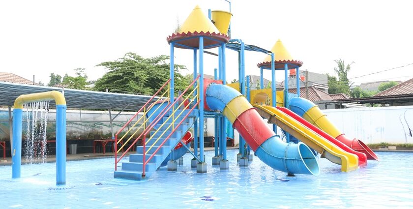 View of a blue, yellow and red water slide and a pool in a water park during the daytime.