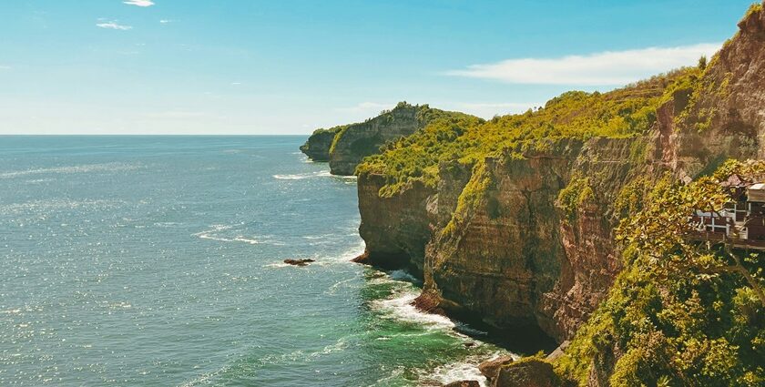 A breathtaking view of a turquoise water body near a lush green cliff during the daytime.