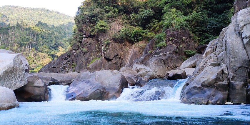 Mesmerising view of Umngot River Waterfall in Meghalaya with lush greenery in background.