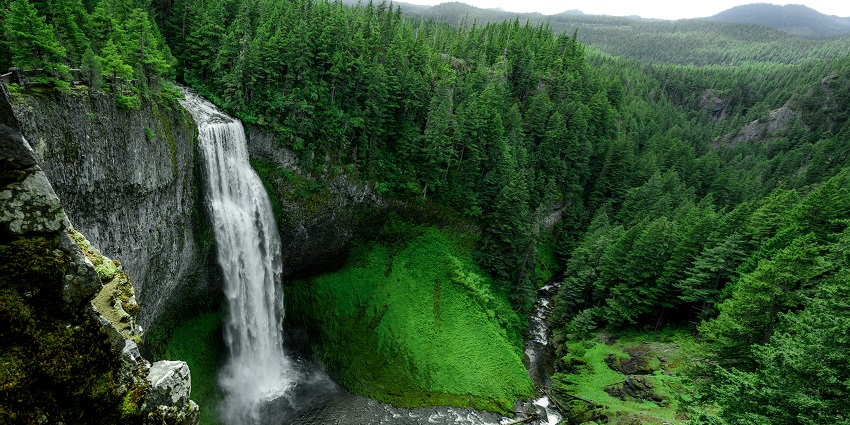 A mesmerising view of a sparkling waterfall surrounded by green meadows during the day.