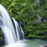 A mesmerising view of a waterfall surrounded by lush greenery during the daytime.