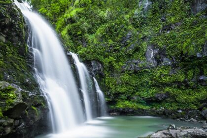 A mesmerising view of a waterfall surrounded by lush greenery during the daytime.