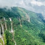 An enchanting view of waterfalls surrounded by lush green meadows during the daytime.