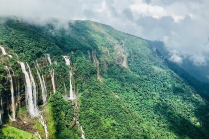 An enchanting view of waterfalls surrounded by lush green meadows during the daytime.