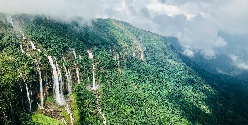 An enchanting view of waterfalls surrounded by lush green meadows during the daytime.