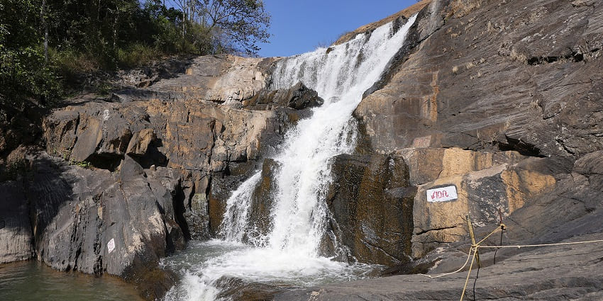 Neer Veezhcha Waterfalls in full flow, surrounded by vibrant flora and tranquil ambience