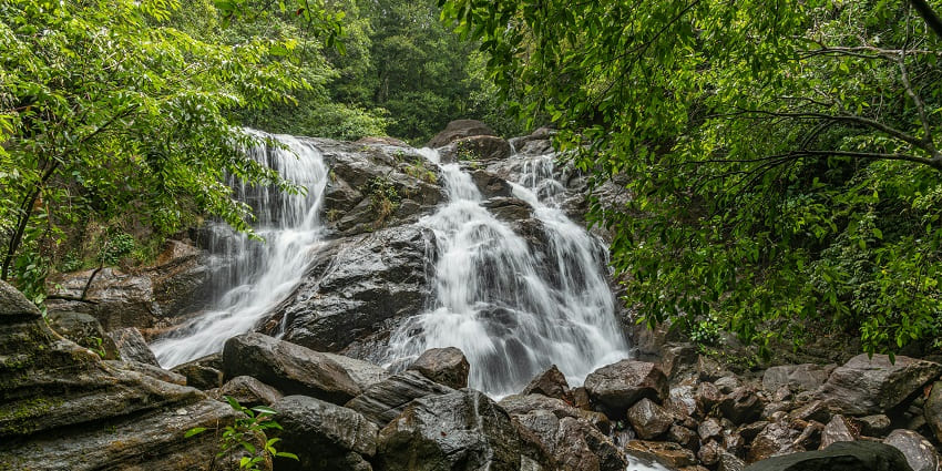 A beautiful waterfall flows over rugged rocks, creating a serene and picturesque natural scene.