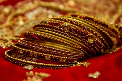 A picture of the bangles of a bride placed on a red cloth with embroidery in a slanting position