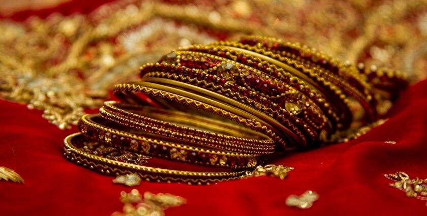 A picture of the bangles of a bride placed on a red cloth with embroidery in a slanting position