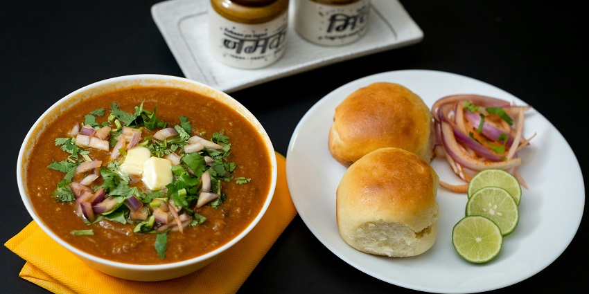A mouthwatering view of a plate served with pav bhaji and garnished with coriander leaves.