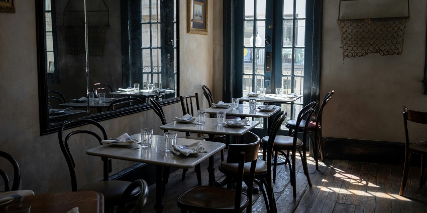 A picture of a restaurant's interiors with a table setting and a cosy ambience with dim lighting